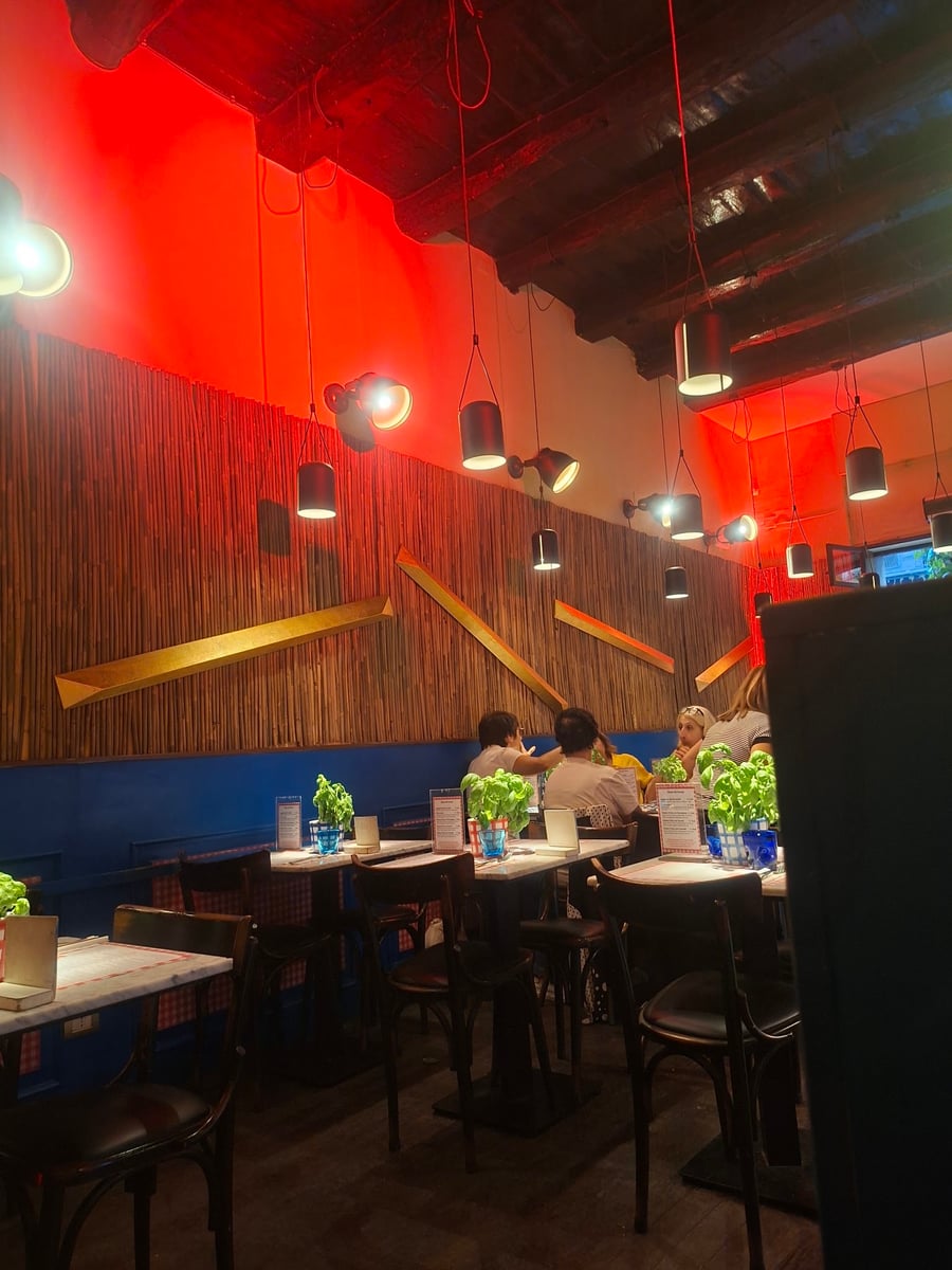 Salão da pizzaria, com a parede de bambu e as luzes vermelhas